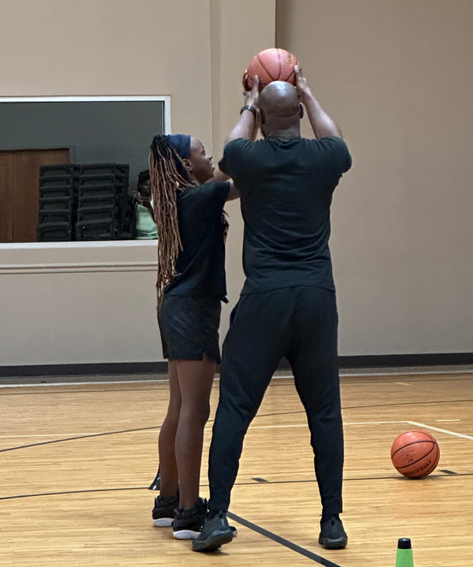 Female player and coach practicing a basketball drill.